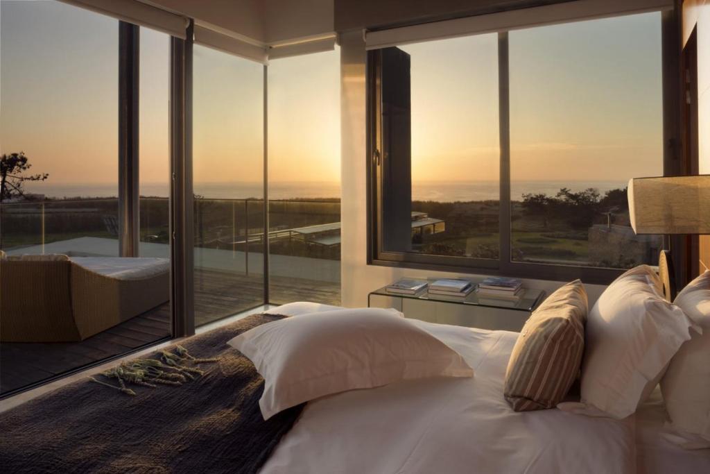 een slaapkamer met een groot bed en grote ramen bij Areias do Seixo Villas in Santa Cruz