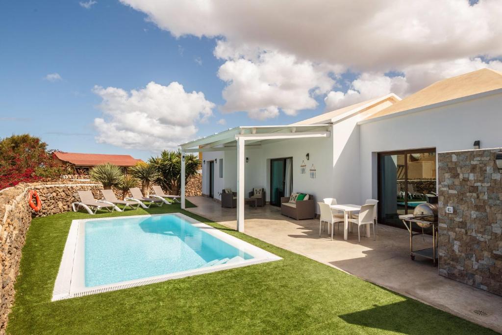 un patio trasero con piscina y una casa en Villa Era, en Cotillo