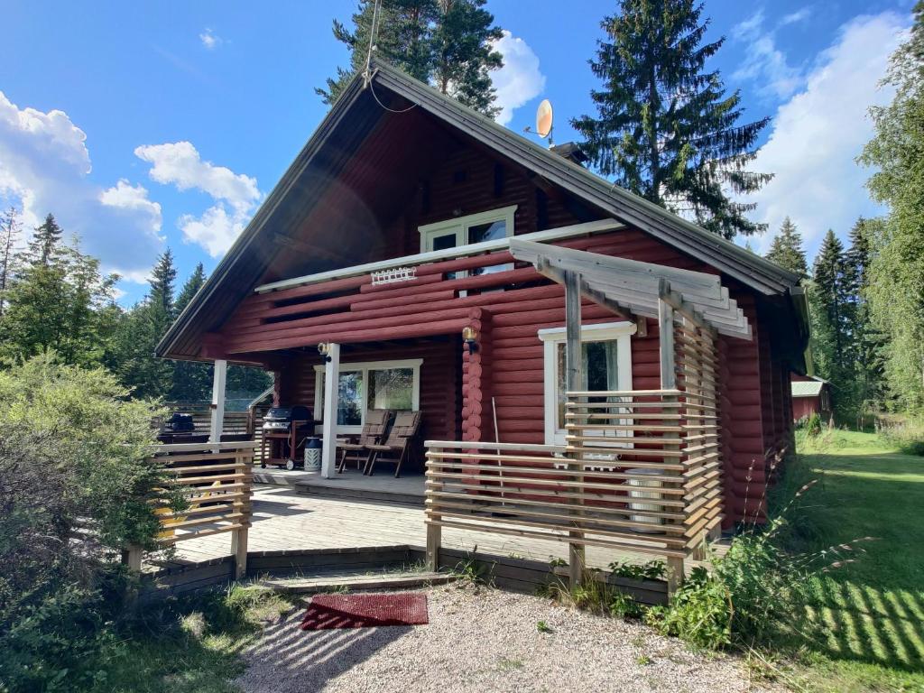 une cabane en rondins dans les bois avec une terrasse couverte dans l'établissement Villa Kotiranta, à Jämsä