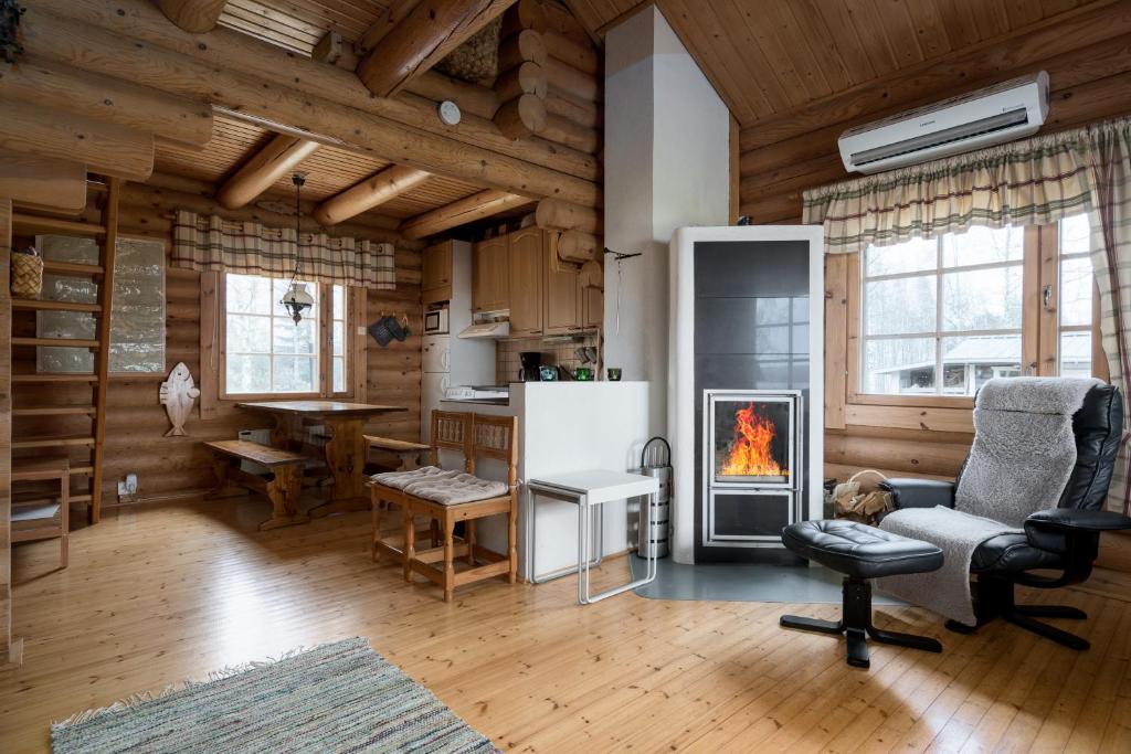a living room with a fireplace in a log cabin at Ainola Cottage in Alapitkä