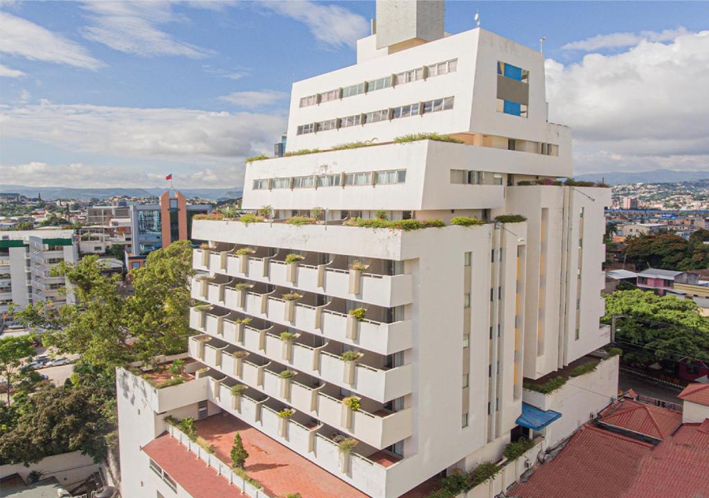 a tall white building with plants on it at Hotel Plaza San Martin in Tegucigalpa