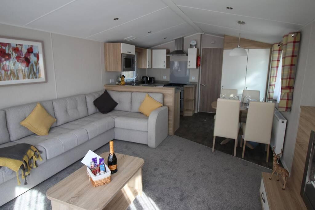 a living room with a couch and a kitchen at The One - Chalet in the Cairngorms in Boat of Garten