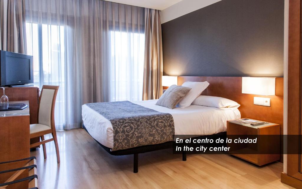 een hotelkamer met een bed, een bureau en een televisie bij Zenit Don Yo in Zaragoza