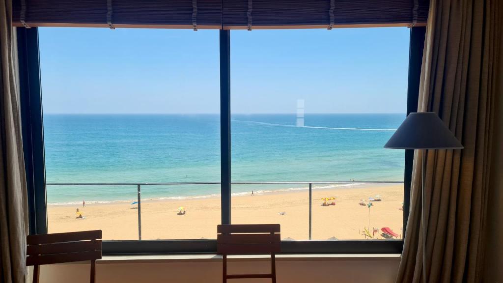 een kamer met uitzicht op het strand vanuit een raam bij Albufeira Beach Cliffs House in Albufeira