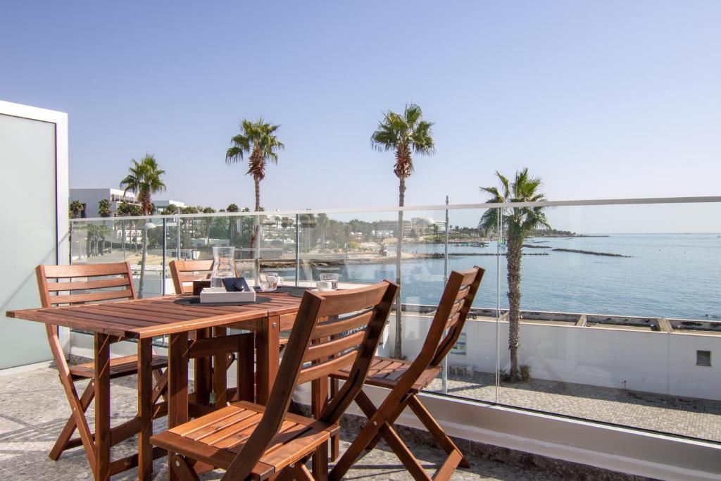 a wooden table with chairs and a view of the ocean at Phaedrus Living Seaview Studio Suite Lighthouse 52 in Paphos