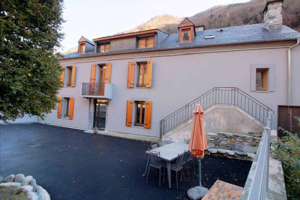 a large white house with a table and an umbrella at Maison de 4 chambres avec jardin clos et wifi a Cauterets a 2 km des pistes in Cauterets