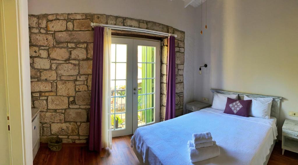 a bedroom with a bed and a stone wall at Oberj d'Azur Alaçatı in Alaçatı