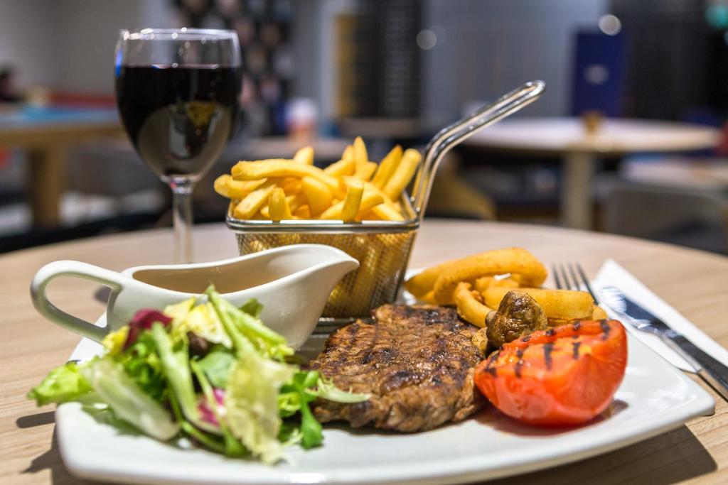 a plate of steak and french fries and a glass of wine at Holiday Inn Express London - Watford Junction by IHG in Watford