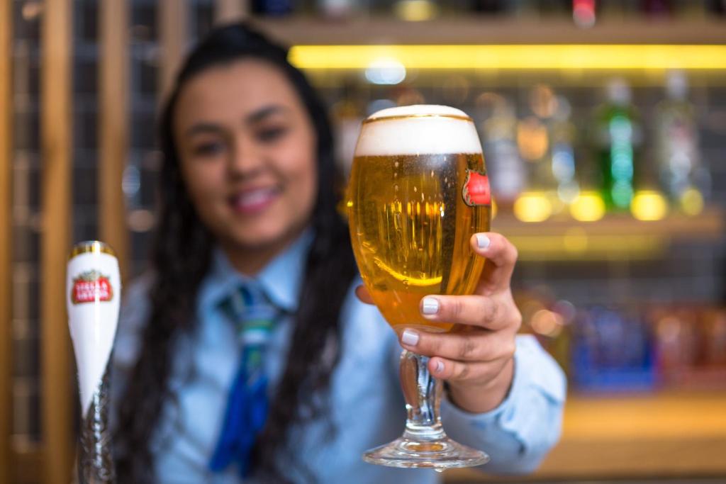 a woman is holding up a glass of beer at Holiday Inn Express London - Watford Junction by IHG in Watford