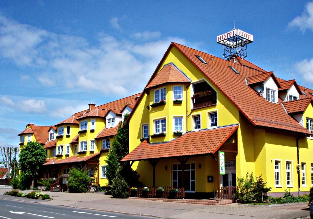 a yellow building with a red roof on a street at Landgasthof Zur Goldenen Aue in Nordhausen