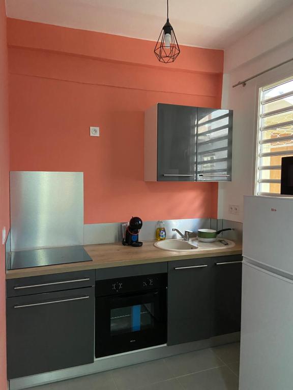 a kitchen with a sink and an orange wall at Kayenn’Apparts in Cayenne