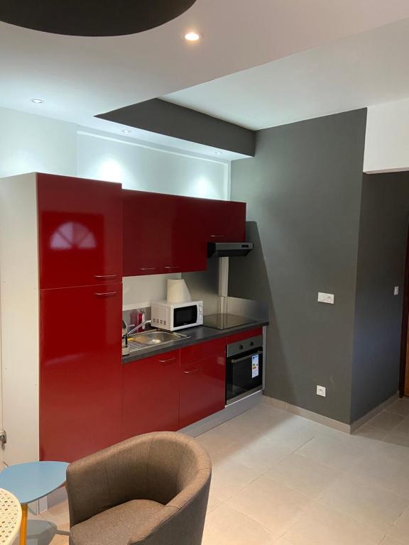 a kitchen with red cabinets and a table and a chair at Kayenn’Apparts in Cayenne