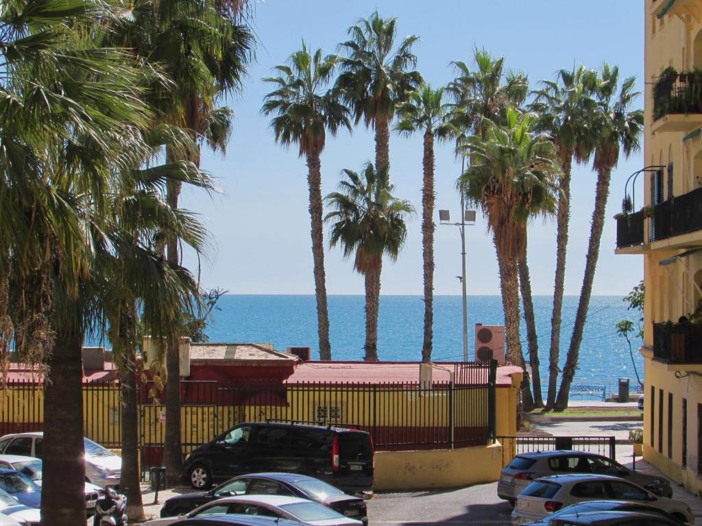 um parque de estacionamento com palmeiras e o oceano em Apartamento a 50 metros de la playa malagueta con vistas al mar em Málaga