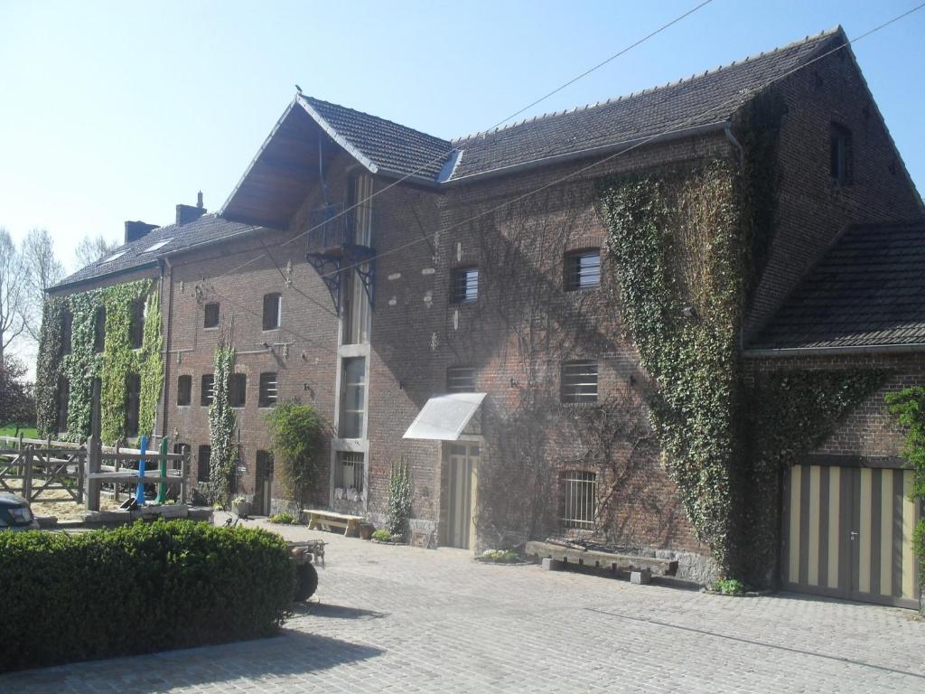 a large brick building with ivy growing on it at B&B Le Moulin de Fernelmont in Forville