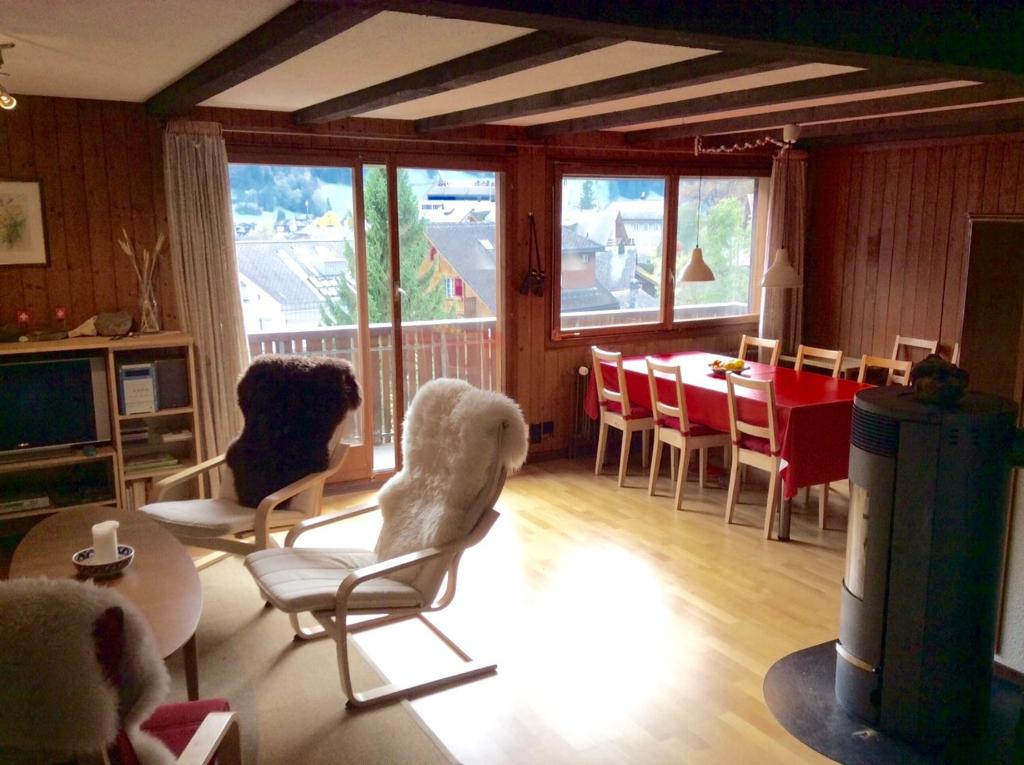 a living room with two dogs sitting in chairs and a table at Gemütliche Dachwohnung im Chalet mit Bergblick in Engelberg