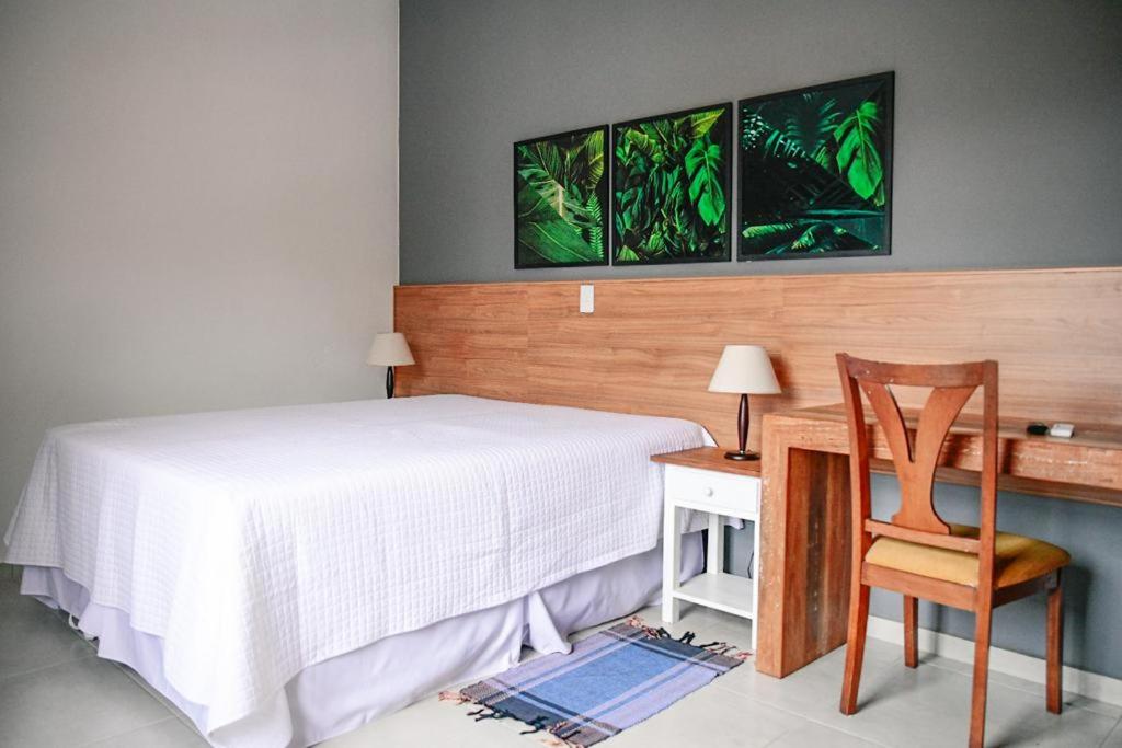 Un dormitorio con una cama y un escritorio con una silla. en Pousada Solmaior, en Conservatória