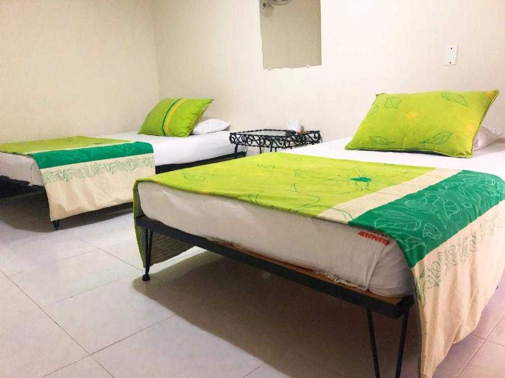 two beds in a room with green and yellow sheets at Hotel Morfeo in Tuluá