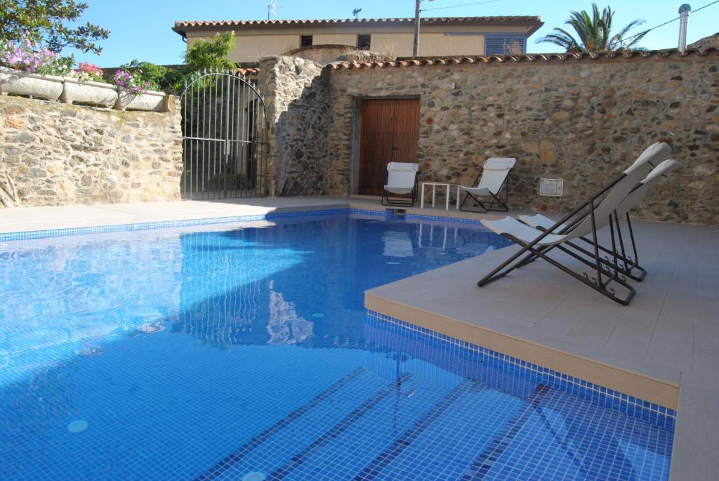 a swimming pool with two chairs sitting next to a building at Can Garriga in Garriguella