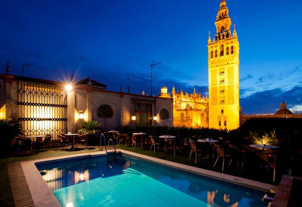 vistas a un edificio con una torre de reloj por la noche en Hotel Doña María en Sevilla