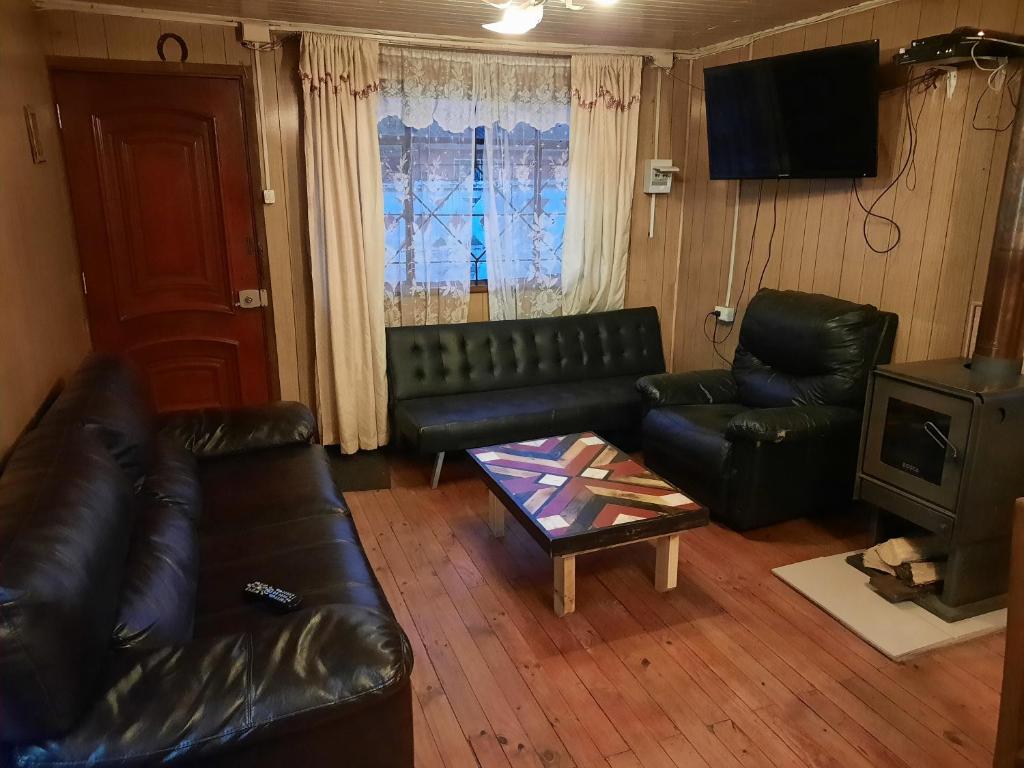 a living room with black leather furniture and a television at casa completa Balmaceda 77 in Concepción