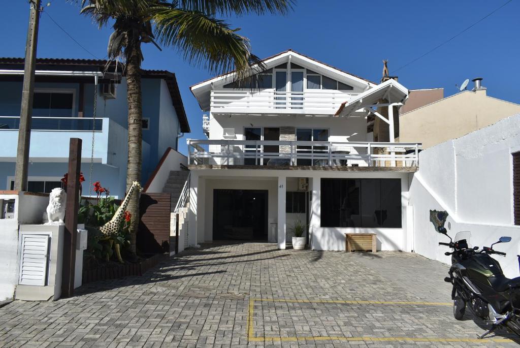 a white house with a balcony and a palm tree at Residencial Morro do Macaco in Bombinhas