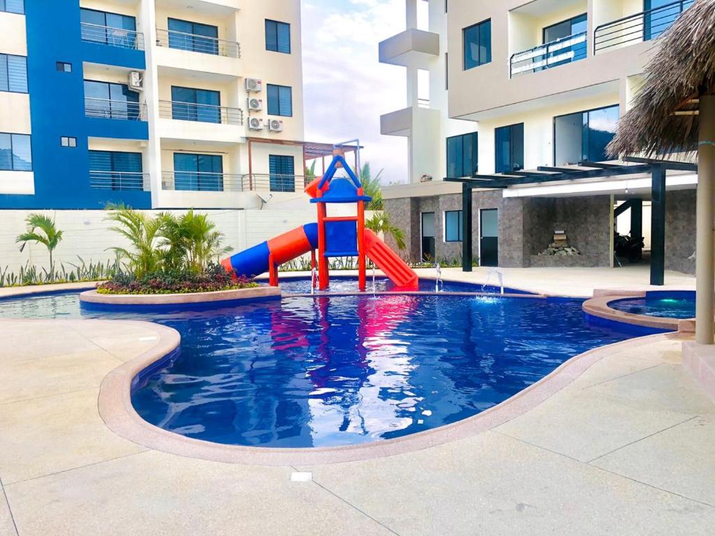 a pool with a slide in the middle of a building at DEPARTAMENTO TOTALMENTE NUEVO, AMOBLADO Y DE LUJO EN TONSUPA in Tonsupa
