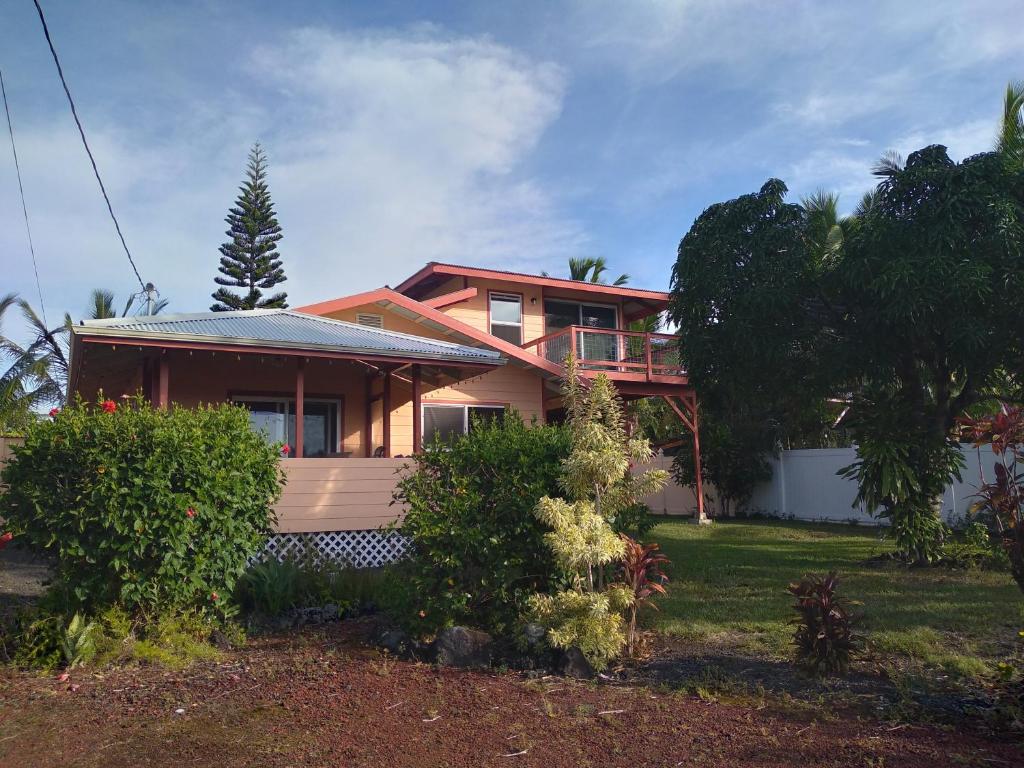 a house with a porch and a yard at Kehena Beach Getaway in Kehena