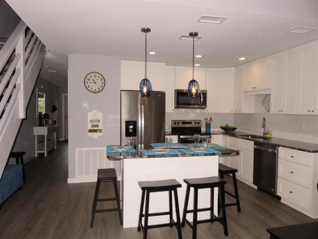 a kitchen with white cabinets and a counter with stools at Our Happy Place in Destin