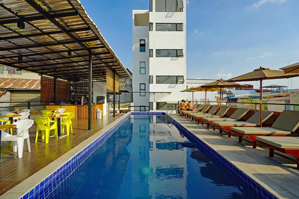 a swimming pool with chairs and tables and a building at Onederz Hostel Phnom Penh in Phnom Penh