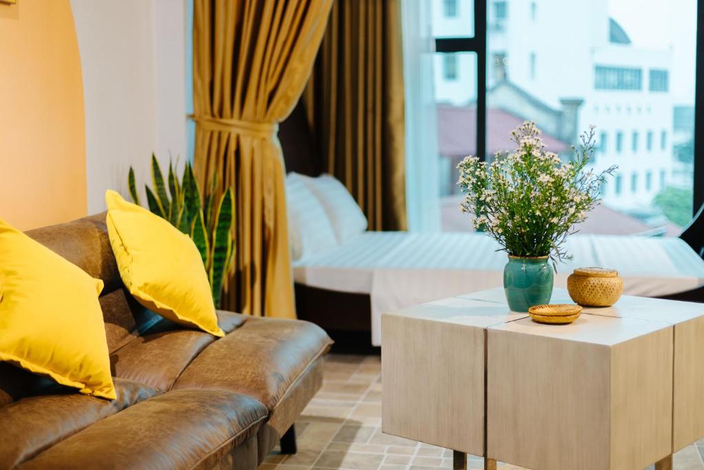 a living room with a couch and a table with flowers at Sunstay Paradise in Hanoi