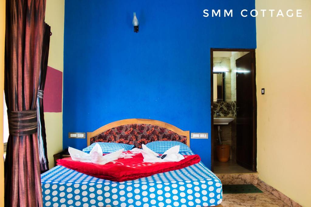 uma cama num quarto com uma parede azul em Smm Cottage em Munnar