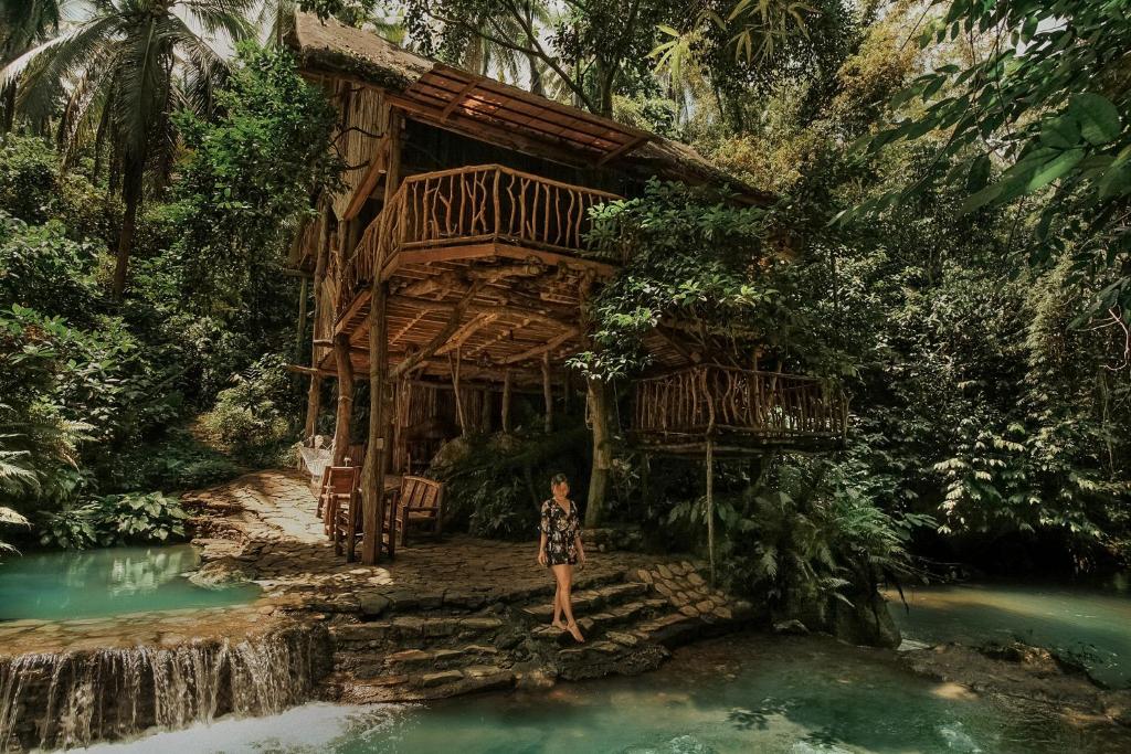 a person standing in front of a house in the water at Treehouse de Valentine in Balamban