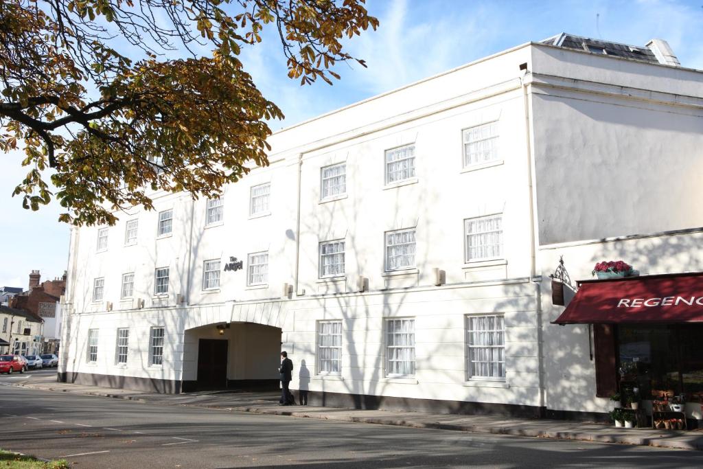 un hombre parado frente a un edificio blanco en The Angel Hotel en Leamington Spa