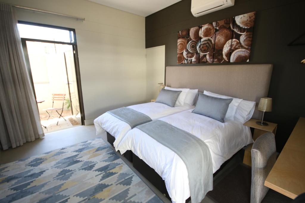 a bedroom with a large bed with a painting on the wall at The Elegant Guesthouse in Windhoek