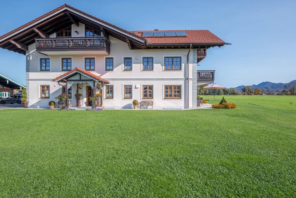 a large white house with a large grass yard at 5 Sterne Ferienwohnung Sissi in Übersee