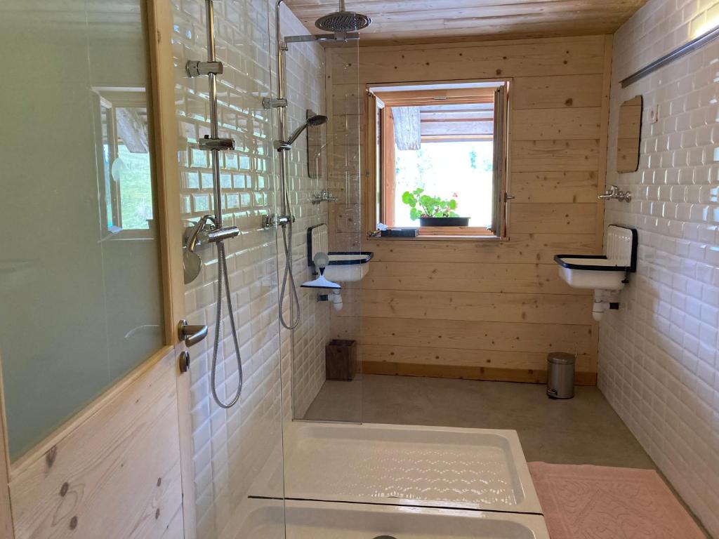 uma casa de banho com um chuveiro, 2 lavatórios e uma janela em Ferme des Moines em Pontarlier