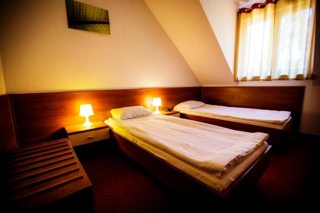 a hotel room with two beds and two lamps at Hotel LUKA in Radom