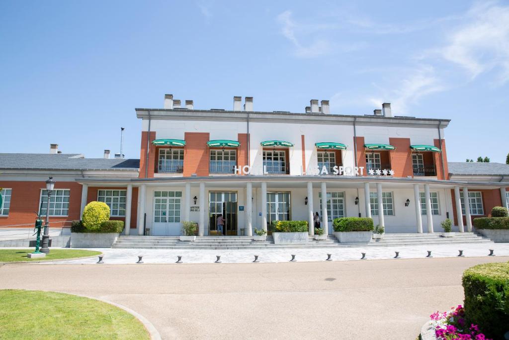 a large red and white building with a courtyard at Hotel Lasa Sport in Valladolid