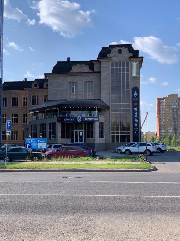 een gebouw met auto's geparkeerd op een parkeerplaats bij MyLINE relax complex in Astana