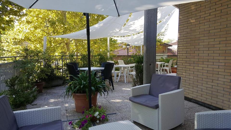 チェゼナーティコにあるHotel Residence Ponenteのパティオ(テーブル、椅子、パラソル付)