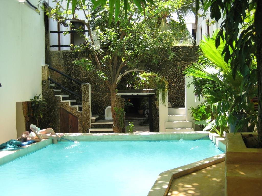 a person laying in a swimming pool next to a building at Jannat House in Lamu