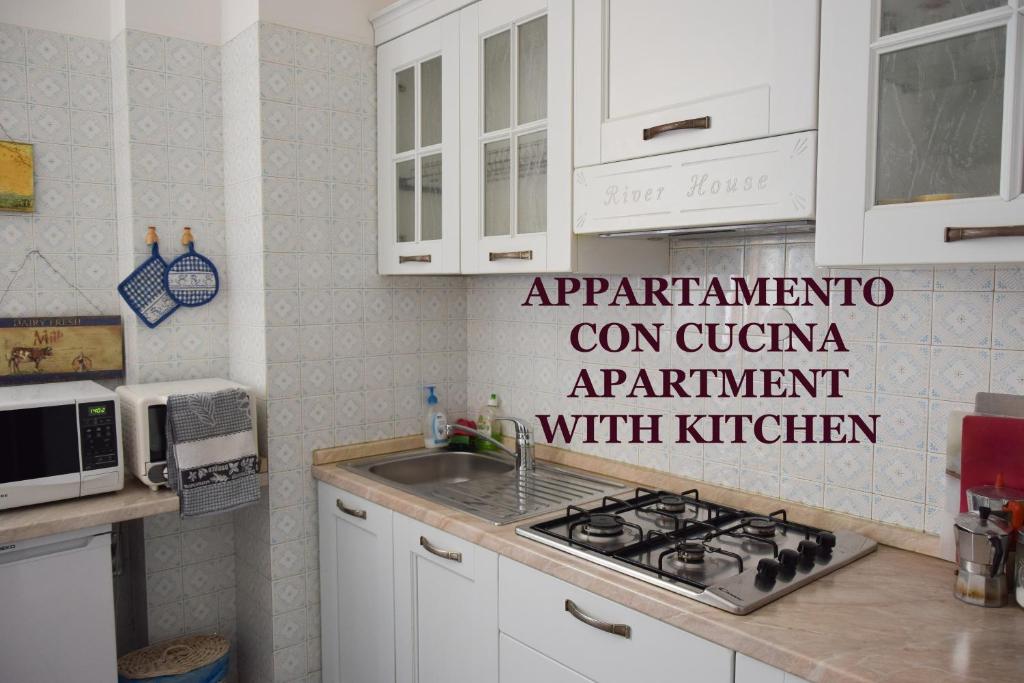 a kitchen with white cabinets and a sink and a stove at River House in Verona