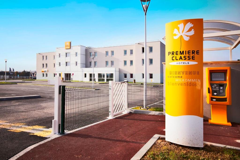 a parking lot with a fence and a gas pump at Premiere Classe Caen Nord - Mémorial in Caen