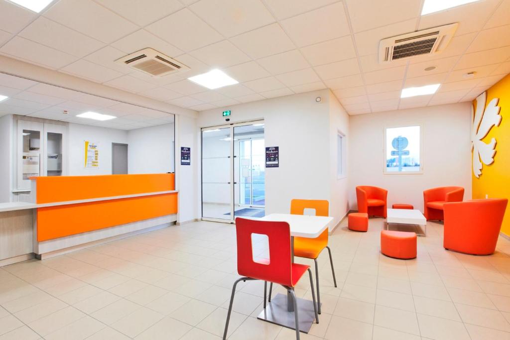 a waiting room at a hospital with orange chairs and tables at Premiere Classe Caen Nord - Mémorial in Caen