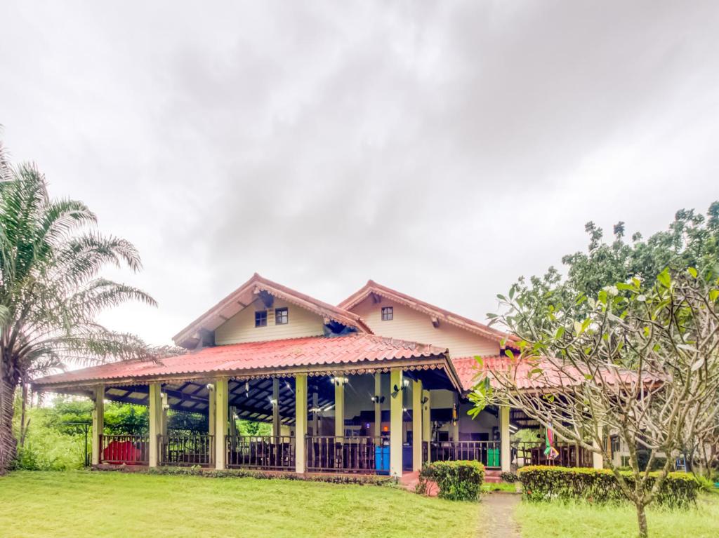 a house with a porch and a green yard at CAPITAL O 1142 Laemkum Beach Resort in Thap Sakae