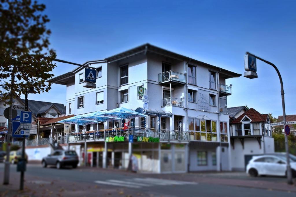 a white building with balconies on a street corner at Zum Treppche Hotel Garni in Gladenbach