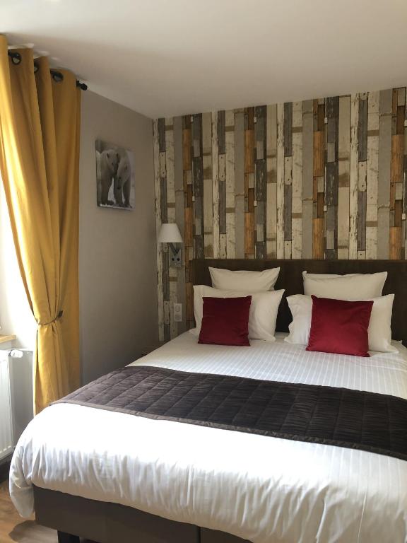 a bedroom with a large bed with red pillows at Hôtel Panorama in Munster