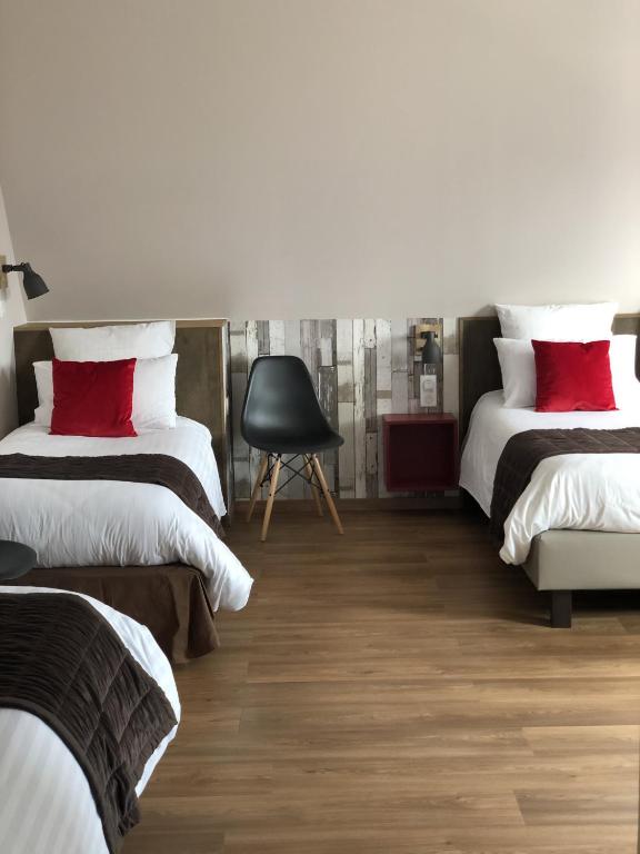 a bedroom with two beds with red pillows and a chair at Hôtel Panorama in Munster