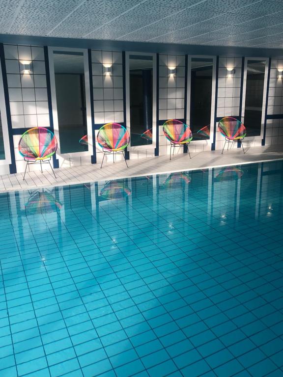 a swimming pool with two chairs and a pool at Hôtel Panorama in Munster