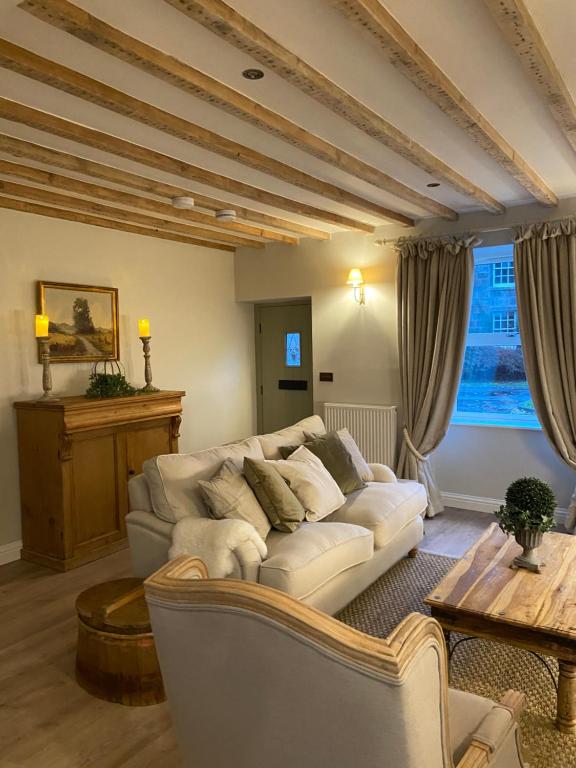 ein Wohnzimmer mit einem weißen Sofa und einem Tisch in der Unterkunft Bailey Cottage in Gargrave